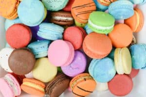 colorful macaroons on top of each other, scattered in a white bowl