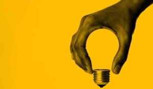 Hand forming a lightbulb with yellow background