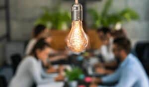Close up of lightbulb with business professionals working in background