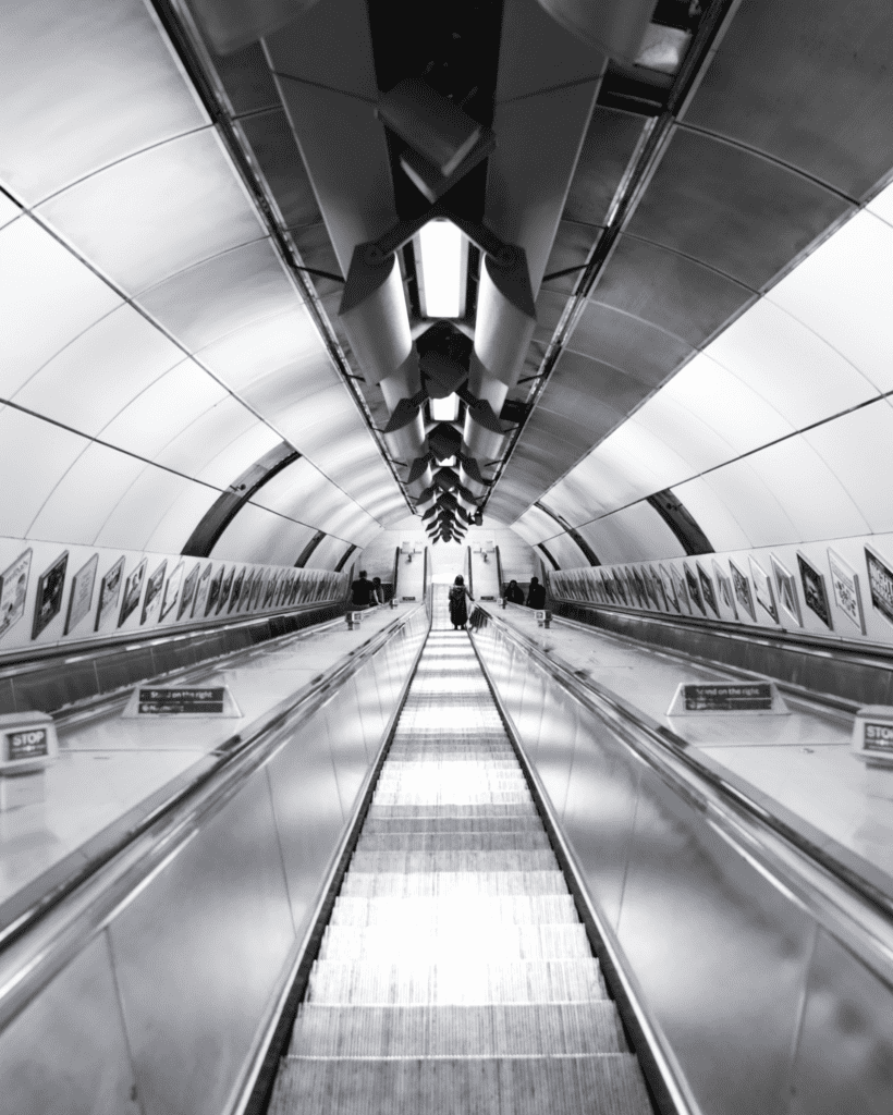 black and white going down a tunnel on an escalator