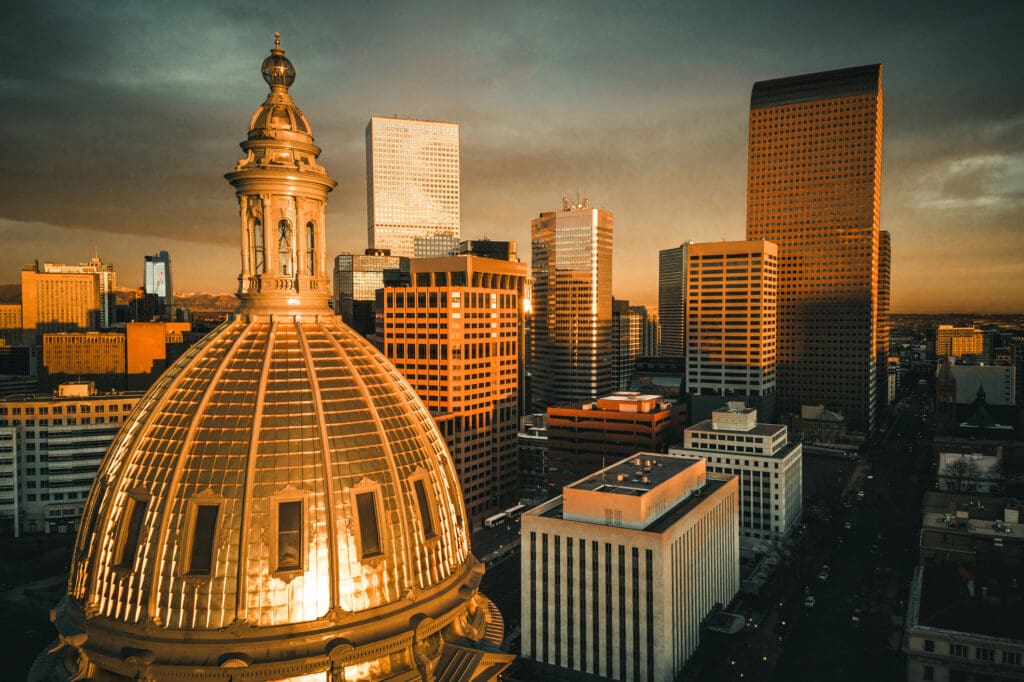 Drone image of Denver featuring the capital dome and high rise buildings at sunrise.