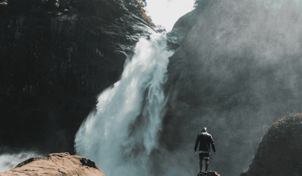 man standing in front of a large waterfall