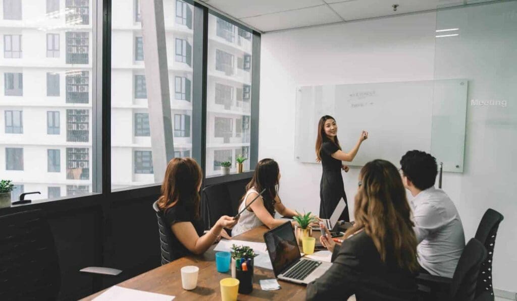 Women writing on white board in business meeting