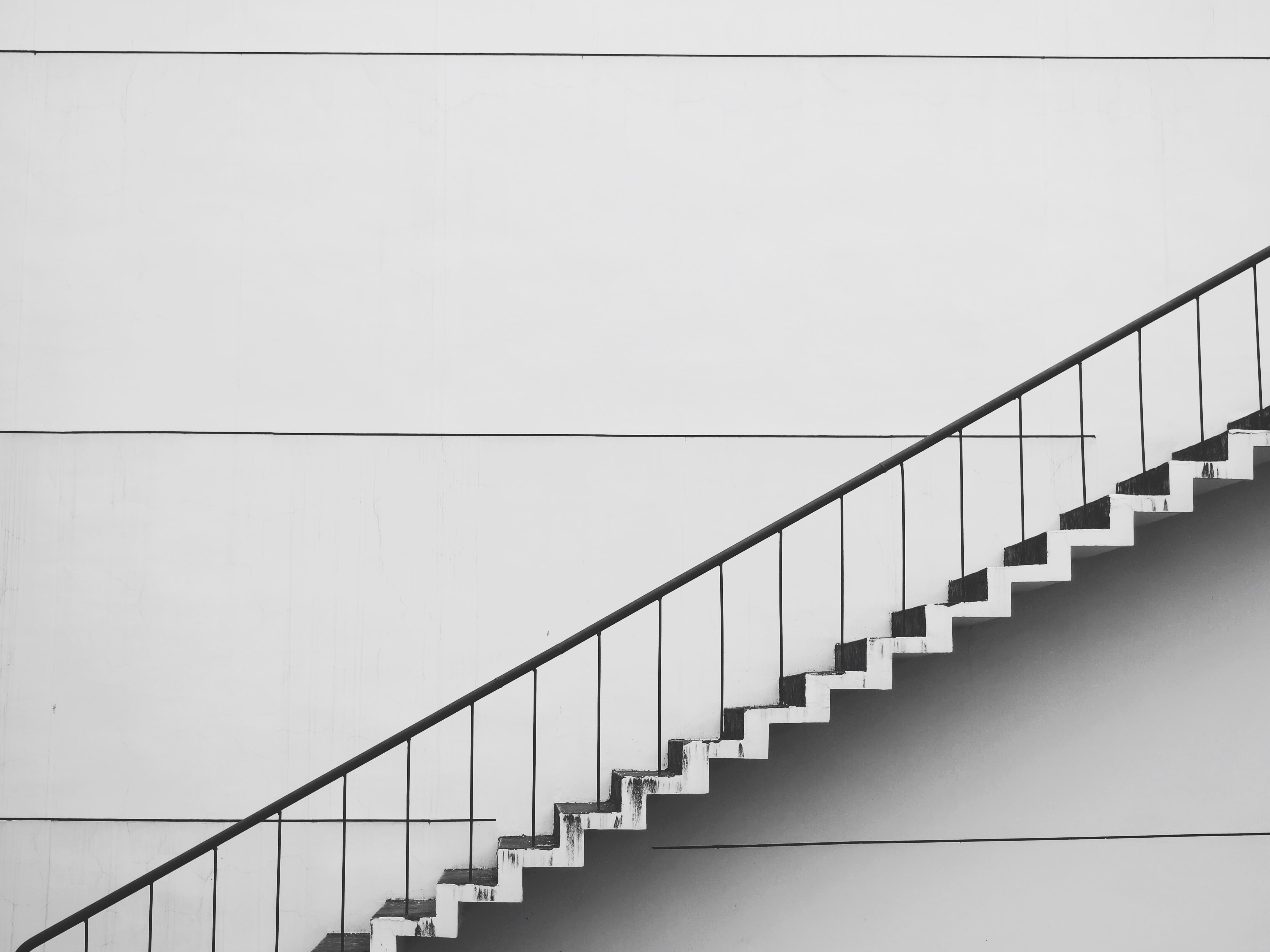 Exterior stairs next to a white wall with a black handrail