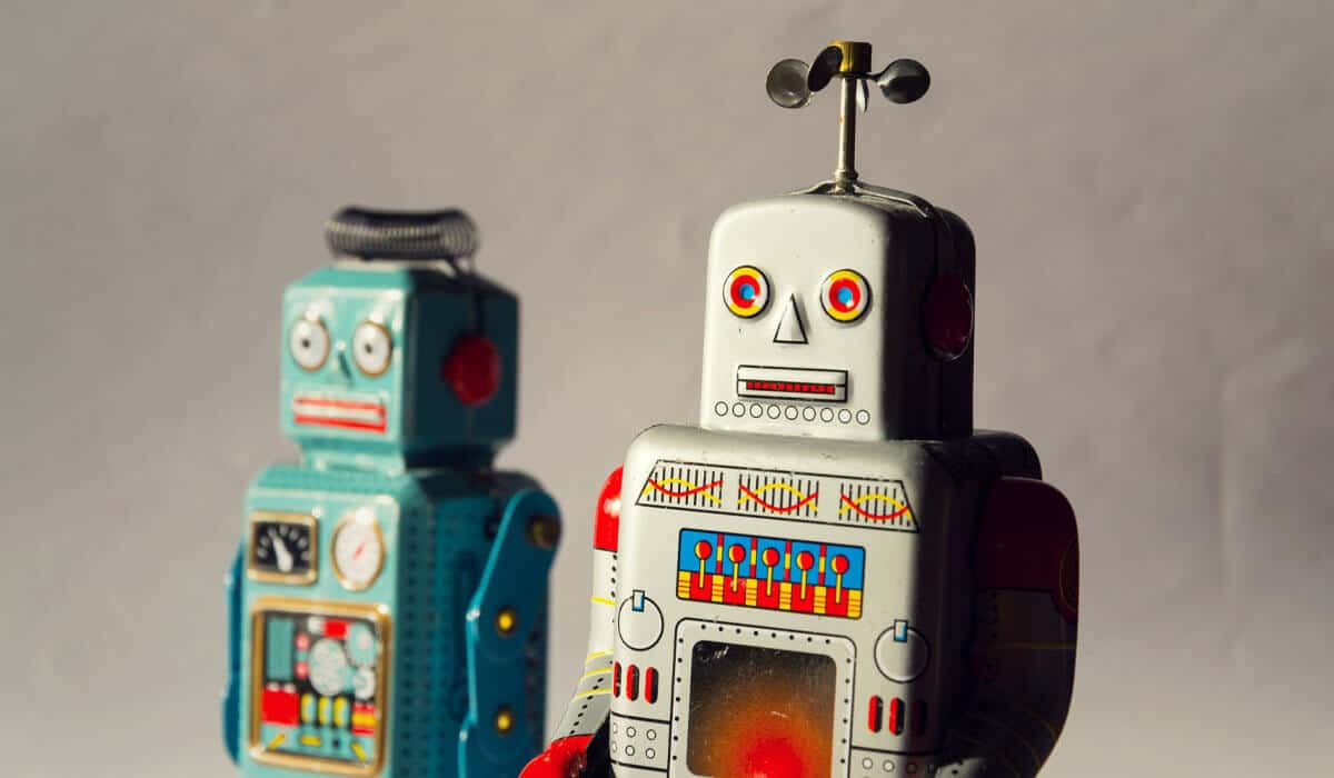 two old school wind up robots in front of a gray background
