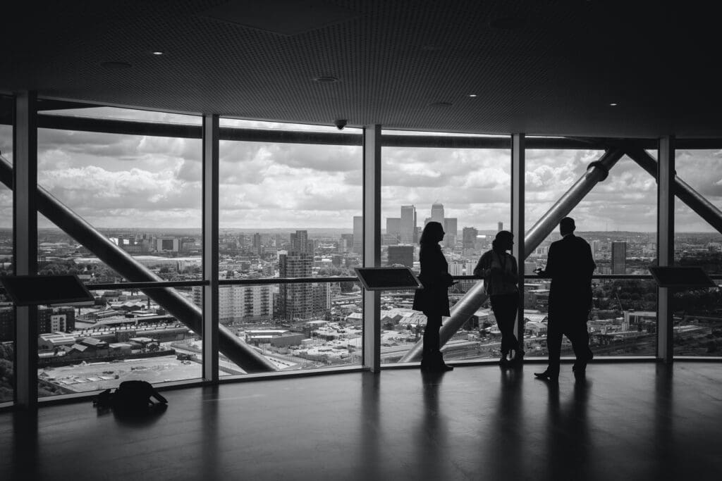 Black and white image of a high-rise office interior with three professionals conversing