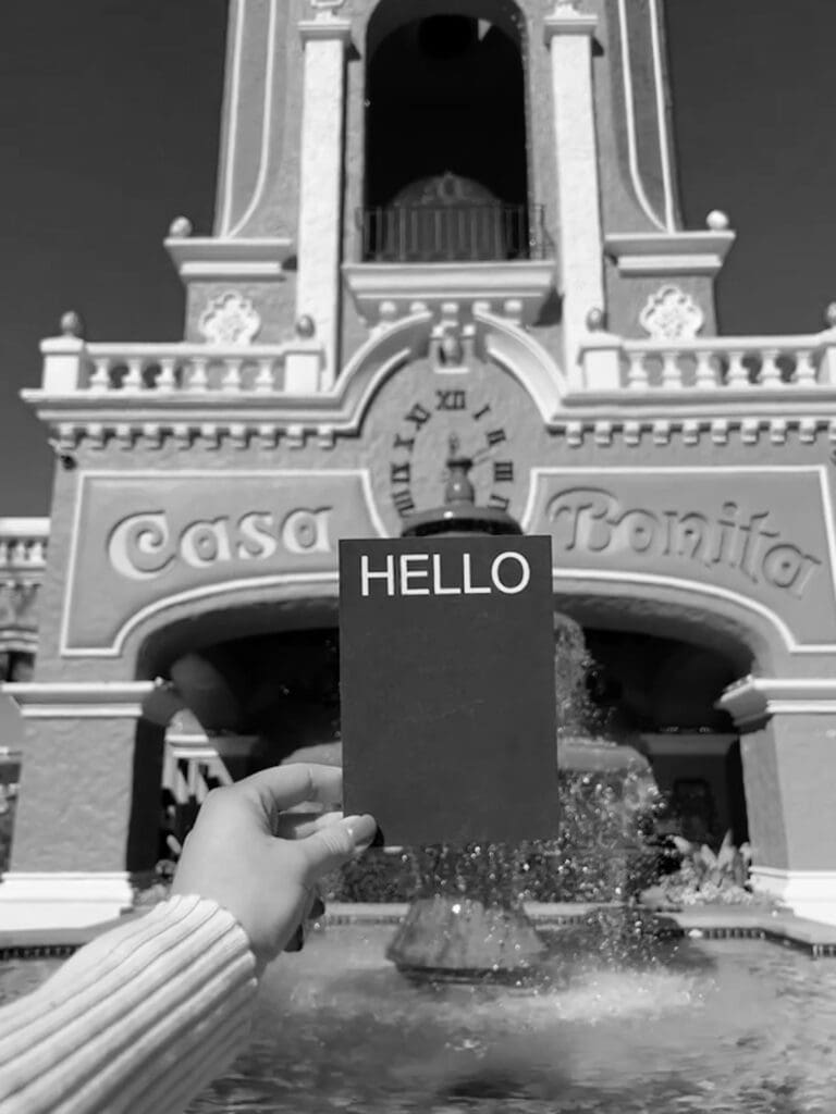 A "Hello" card in front of the entrance to Denver restaurant "Casa Bonita", black and white