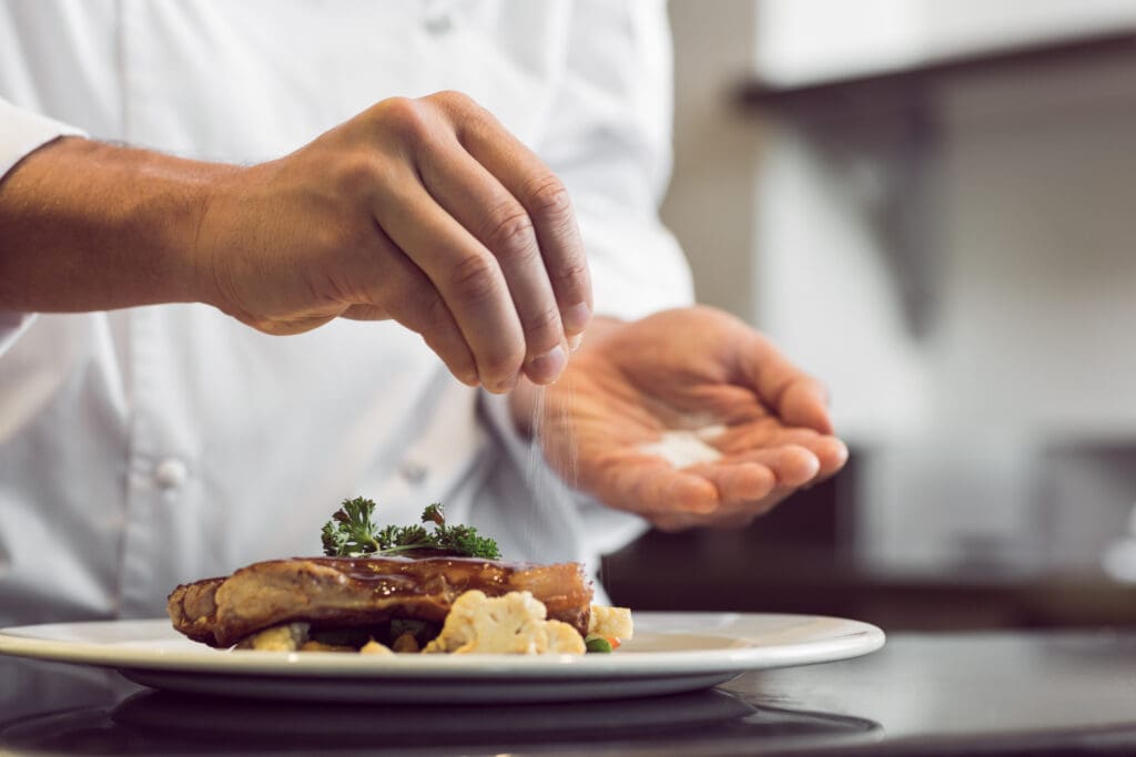 Chef adding salt to a prepared dish