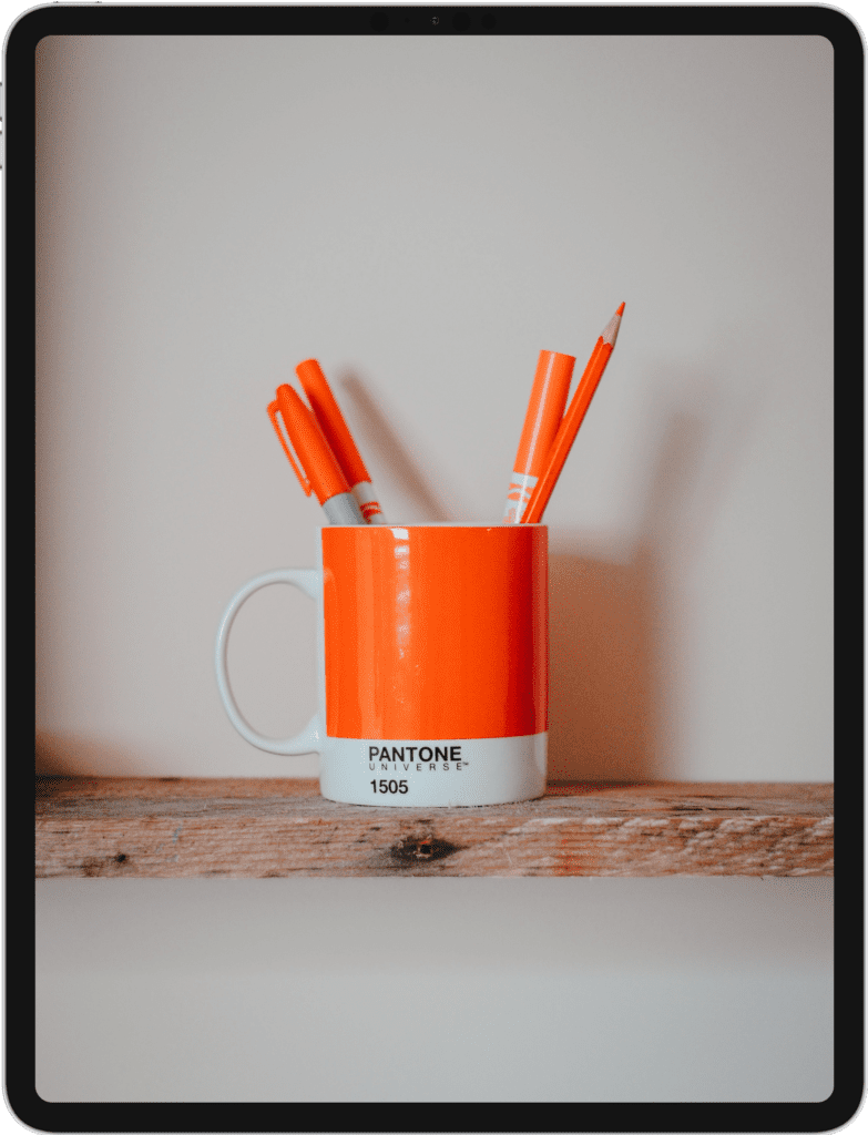 iPad Pro screen featuring a orange coffee cup with orange writing untensils inside