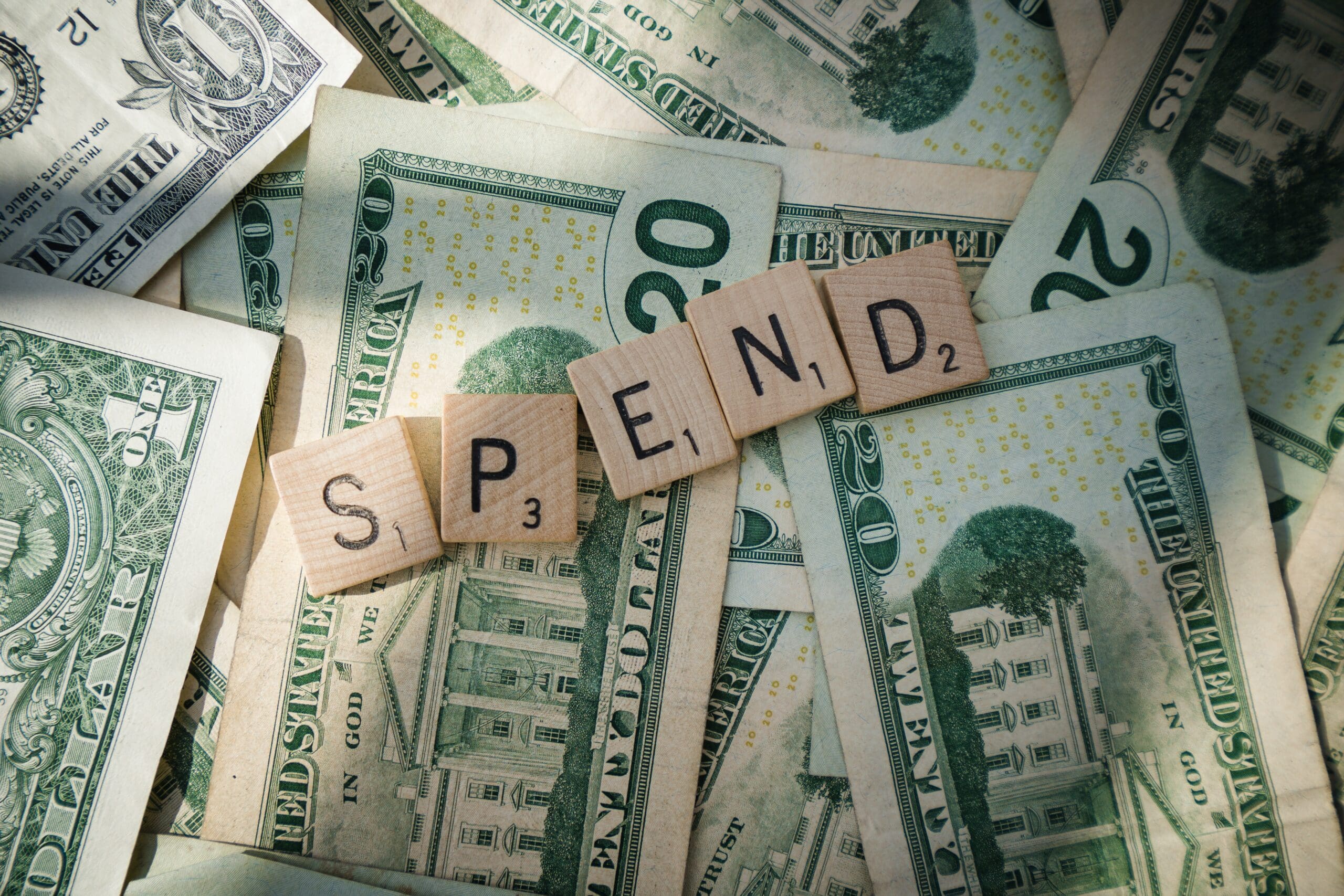 Scrabble letters spelling "Spend" on 20 dollar bills