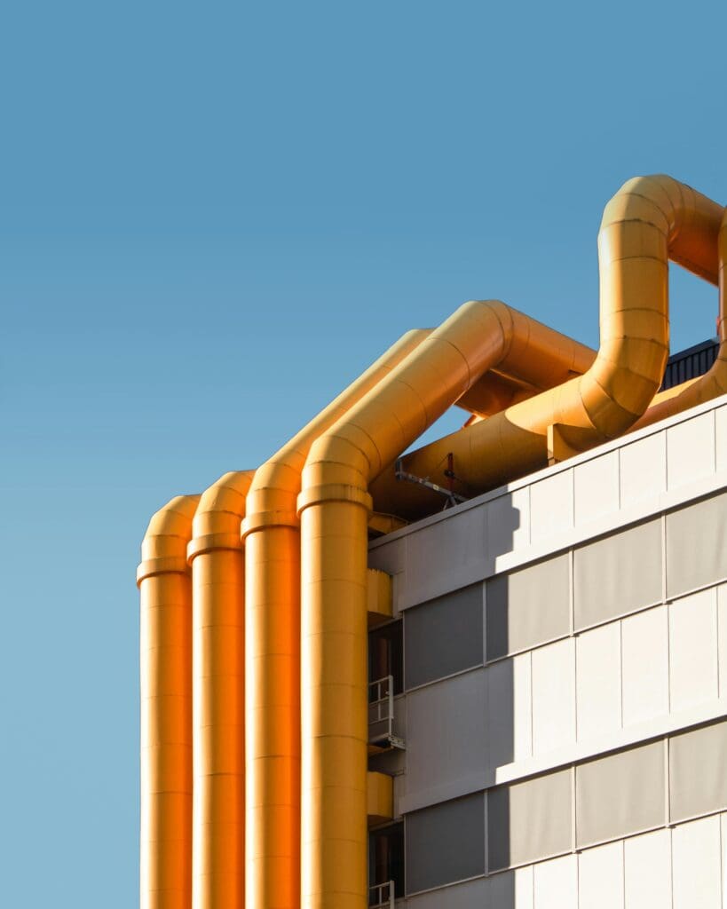 Yellow pipes along the side of a building against a blue sky