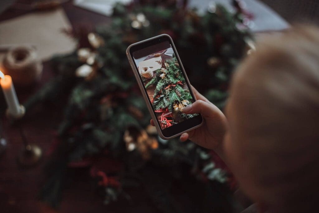 Person taking a photo on their smart phone of christmas decorations