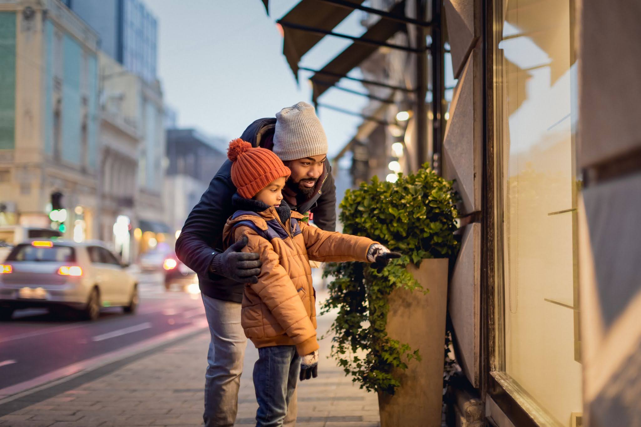 Father and daughter looking at a shop window during the winter